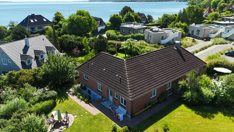 Luftaufnahme des Hauses und des umgebenden Gartens, dahinter die Förde